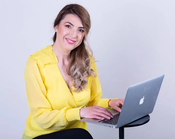 Andreea Giurgilă, coach profesionist, lucrând la laptop pentru o sesiune de coaching online