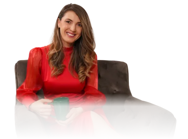 Andreea Giurgilă, NLP Master Coach, zâmbind, în rochie roșie, pe un fotoliu, cu o cană în mâini